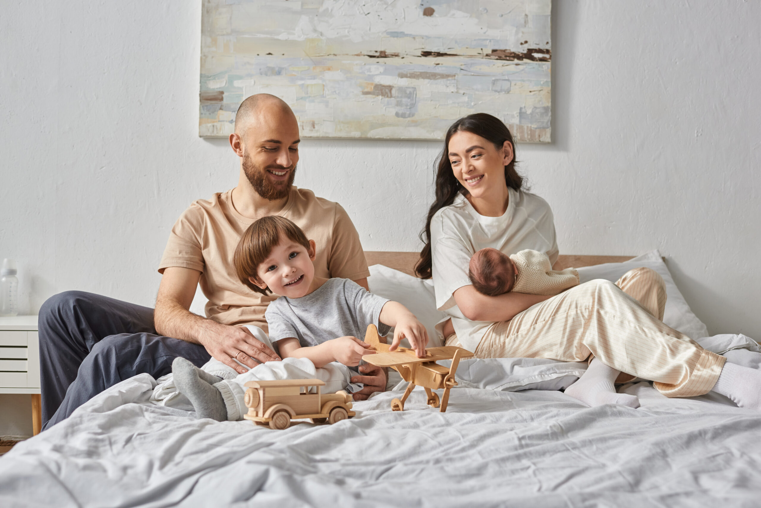joyous family having great time together relaxing in bed and smiling at each other, modern parenting